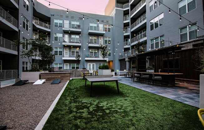 A grassy courtyard with a bench and a table surrounded by apartment buildings.
