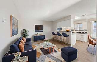 A living room with a dark blue couch and a coffee table with a vase of flowers on it.