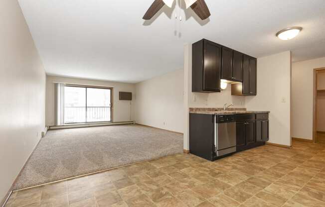 Anoka, MN Dellwood Estates Apartments. a kitchen and living room with a large window and a ceiling fan