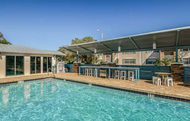 a swimming pool with a patio with chairs and a house with a pool