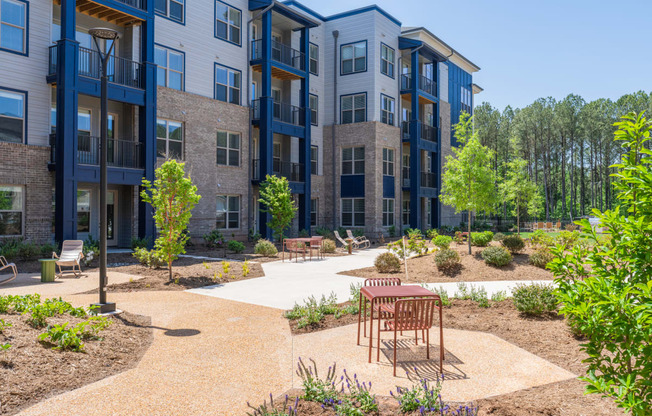 an outdoor area with a table and chairs in front of an apartment building at Preston Ridge, North Carolina