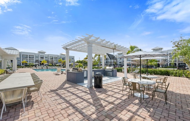 an outdoor patio with tables, grills and chairs and a swimming pool
