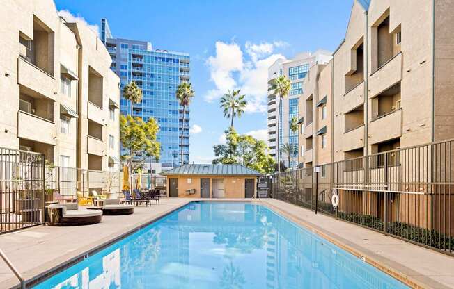 A pool surrounded by buildings and palm trees.