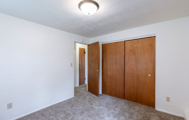 a bedroom with white walls and wooden doors and a ceiling light. Fargo, ND Spring Apartments