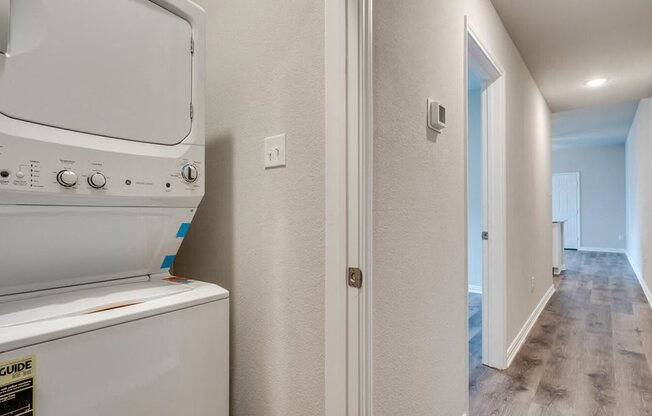 a laundry room with a washer and dryer and a hallway with a door