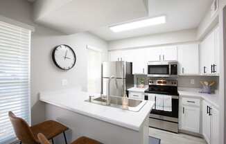 a kitchen with white cabinets and a large clock on the wall