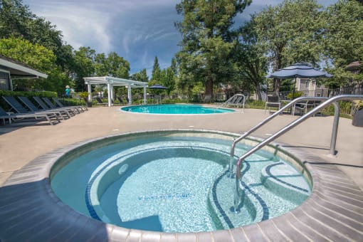Pool with a hot tub and lounge chairs