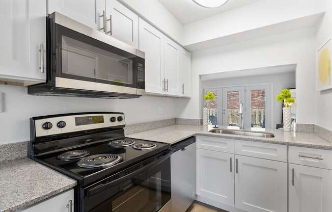 Updated kitchen at Monon Living with stainless steel appliances, granite counters, and stylish cabinetry in a pet-friendly community near the Monon Trail.