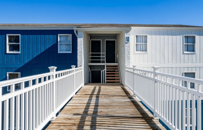 a blue and white house with a porch and a boardwalk