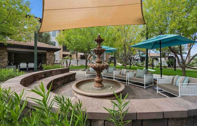 A fountain in the middle of a patio with a shade sail over it. at The Laurel Apartments, Chandler, AZ