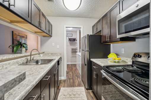 A kitchen with black appliances and a marble countertop.