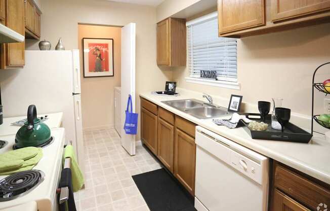A kitchen with a white fridge and a green kettle.