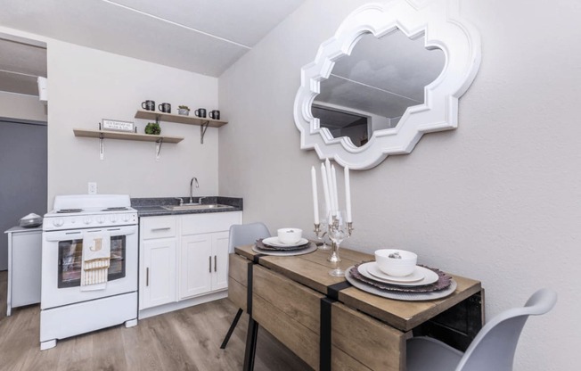 A modern kitchen with a white oven and a wooden dining table set with plates.
