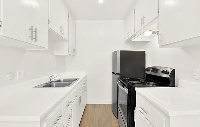 A white kitchen with a black stove top oven.