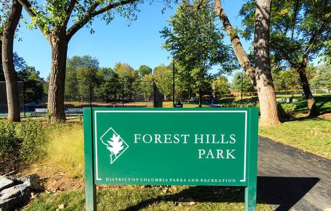 a sign for forest hills park in front of trees