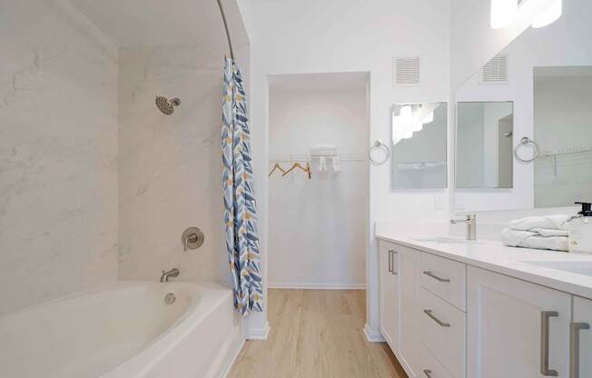 A white bathroom with a tub, sink, and mirror.