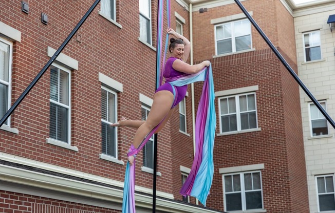 a woman hanging from a pole in front of a brick building