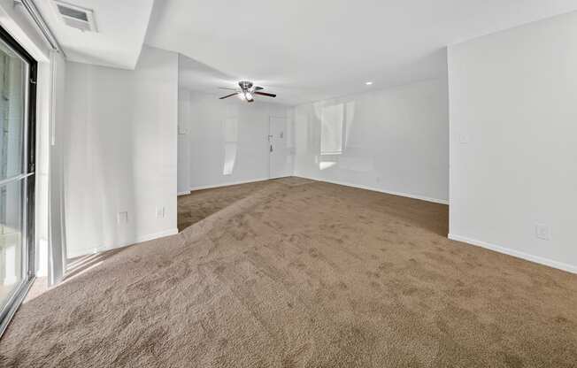 A room with a carpeted floor and a ceiling fan.