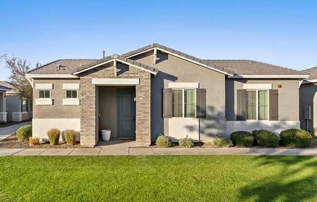 A modern house with a grey roof and a grey front yard.