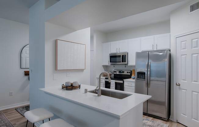 a kitchen with white cabinets and stainless steel appliances