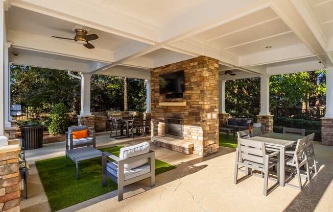 a covered patio with a table and chairs and a fireplace