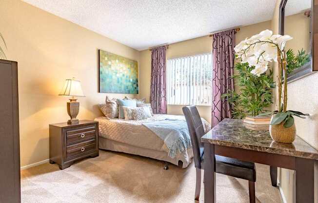A bedroom with a bed, a chair, a nightstand, and a painting on the wall.