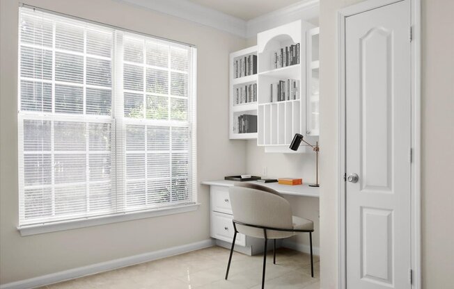 a home office with a desk and a chair in front of a window