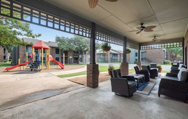 a covered patio with furniture and a playground in the background