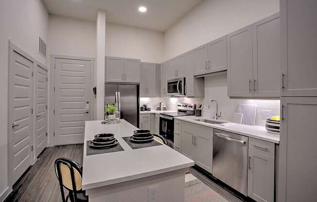 A kitchen with white cabinets and a white island with plates on it.