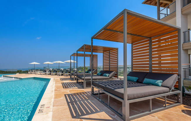 a swimming pool with chaise lounge chairs and a poolside cabana with a