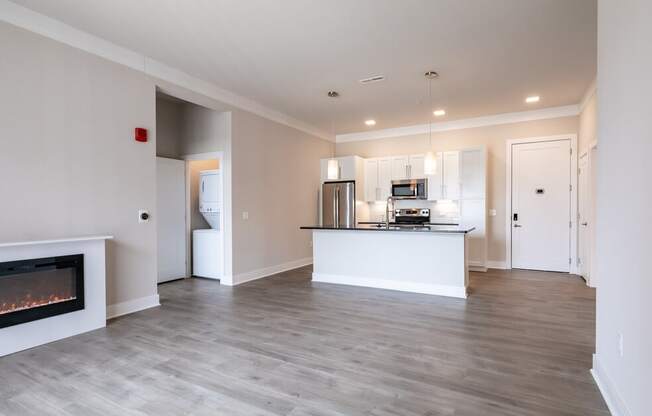 a living room with a fireplace and a kitchen in the background