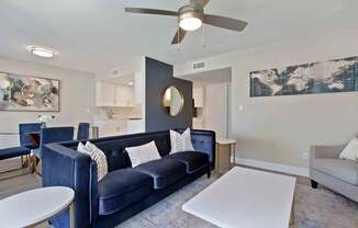 A living room with a blue couch and a white coffee table.