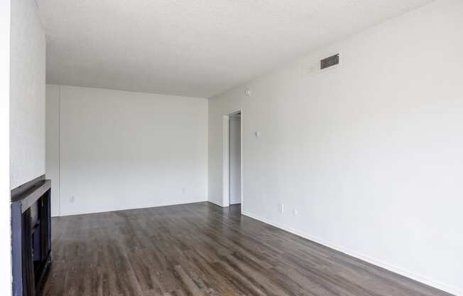 an empty living room with white walls and wood floors