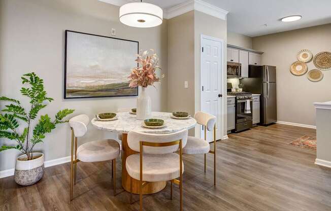 A dining room with a table set for four and a painting on the wall.