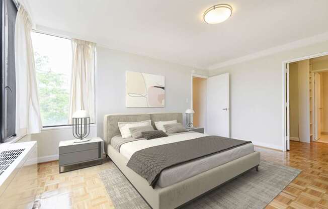 A bedroom with a large bed and a window with curtains.