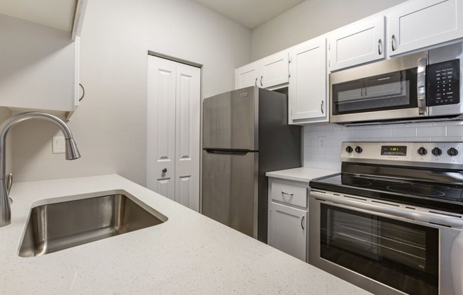 Experience culinary bliss in our sleek kitchen adorned with pristine white cabinets and modern stainless steel appliances at Boulders at Lookout Mountain Apartment Homes, Phoenix, AZ