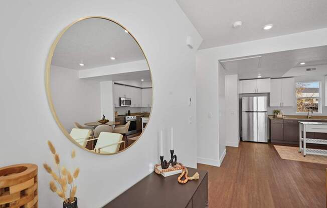 a living room with a large mirror and a kitchen in the background
