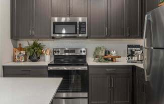 A modern kitchen with dark wood cabinets and stainless steel appliances.