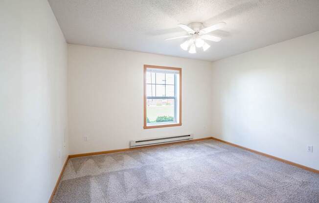 A room with a carpeted floor and a window. Fargo, ND Stonebridge Apartments