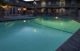 a large pool at night with a hotel in the background