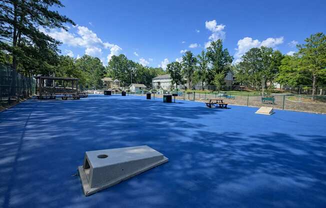 A playground with a blue surface and a slide in the foreground.