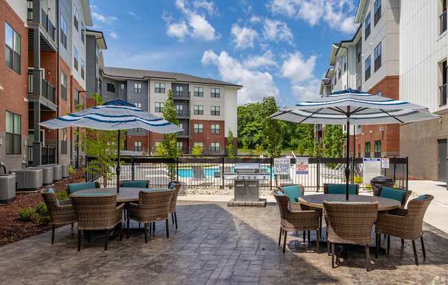 A patio with chairs and umbrellas overlooking a pool.