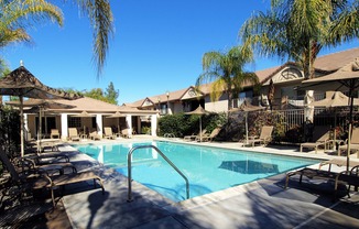 pool with lounge chairs and umbrellas at Cypress Villas Apartments