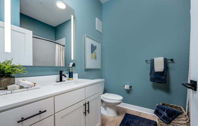 a bathroom with a blue wall and white cabinets