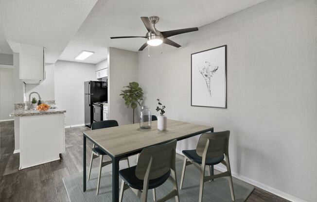 A dining area with a table and chairs and a kitchen in the background