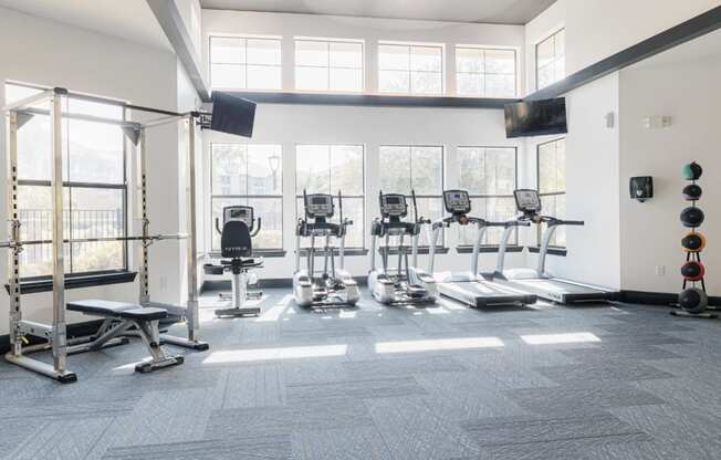 a gym with cardio equipment and windows in a building