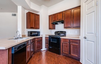 an empty kitchen with wooden cabinets and a black stove and oven