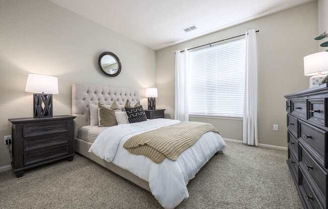 A bedroom with a large bed, a dresser, and a mirror on the wall.