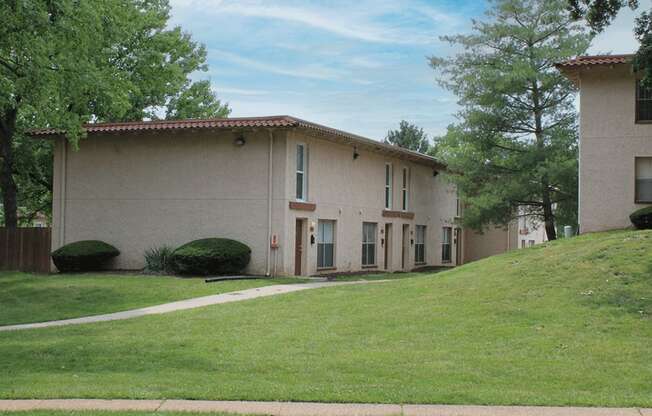 a picture of the front of a tan building with a green lawn