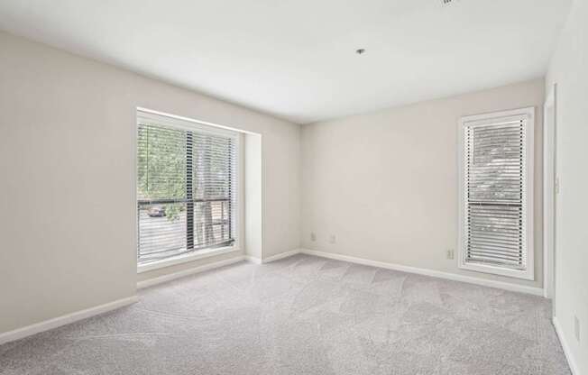 A large bedroom with a carpeted floor and windows